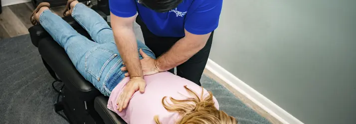 Chiropractor performing spinal adjustment on a patient lying face down