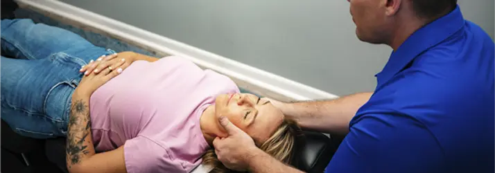 Chiropractor Martinsville IN Curtis Legg Neck Pain Dr. Curtis Legg performing neck adjustment on a patient lying on treatment table at Indiana Family Chiropractic Center
